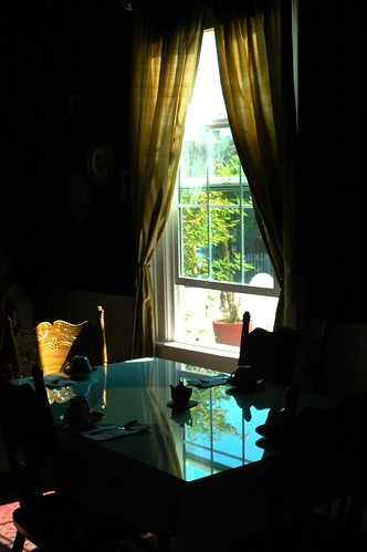 Tea house table in the dark interior room, window, tea pot, glass reflection, wood chairs, Southern California, USA
