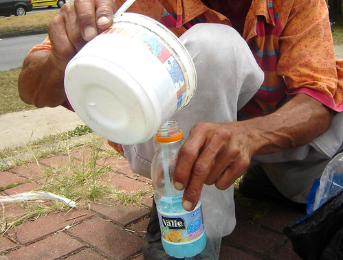 Octavio pasa la solución de detergente en polvo, champú y agua de un recipiente de boca ancha a una botella.