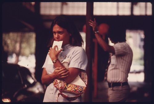 Student Nurse Stands Deep in Thought Waiting for Her Car to Complete Testing at an Auto Emission Inspection Station in Downtown Cincinnati, Ohio...09/1975