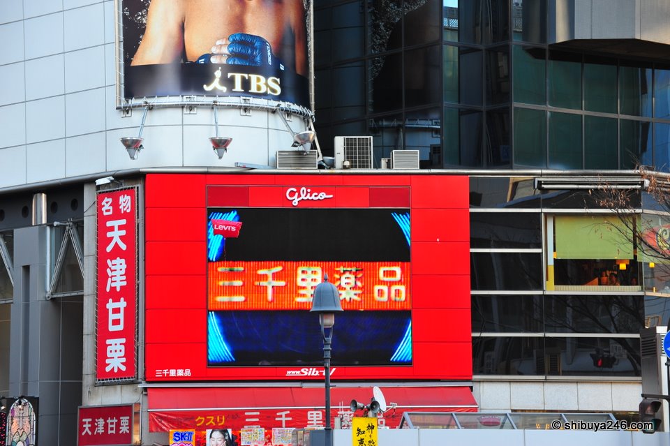 A LEVI'S balloon escaping a customers grip, takes a quick break for some free advertising in front of the glico electronic billboard.