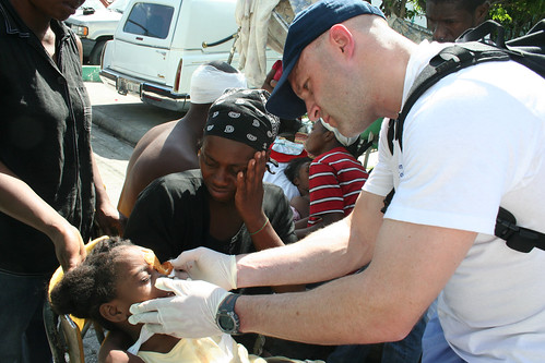 A member of the International Medical Corps treats a small child's injured eye outside a Port-au-Prince hospital. 