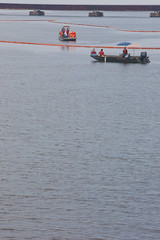 A boat supervises another boat laying boom in a harbor of Biloxi, Mississippi - TEDx Oil Spill Expedition