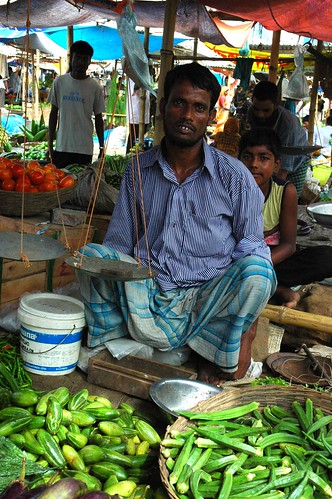 Market vendor with scales, okra, eggplant, squash, green beans, vegetables, Dhaka, Bangladesh by Wonderlane