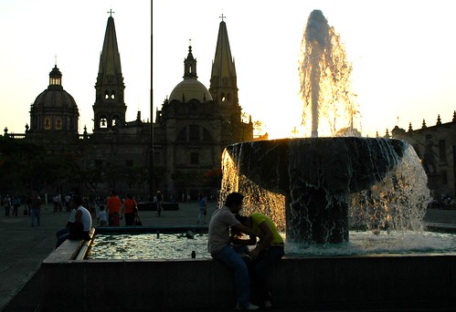 A couple goofing around at a fountain, sunset, main cathedral, executive square, downtown, Guadalajara, Jalisco, Mexico
