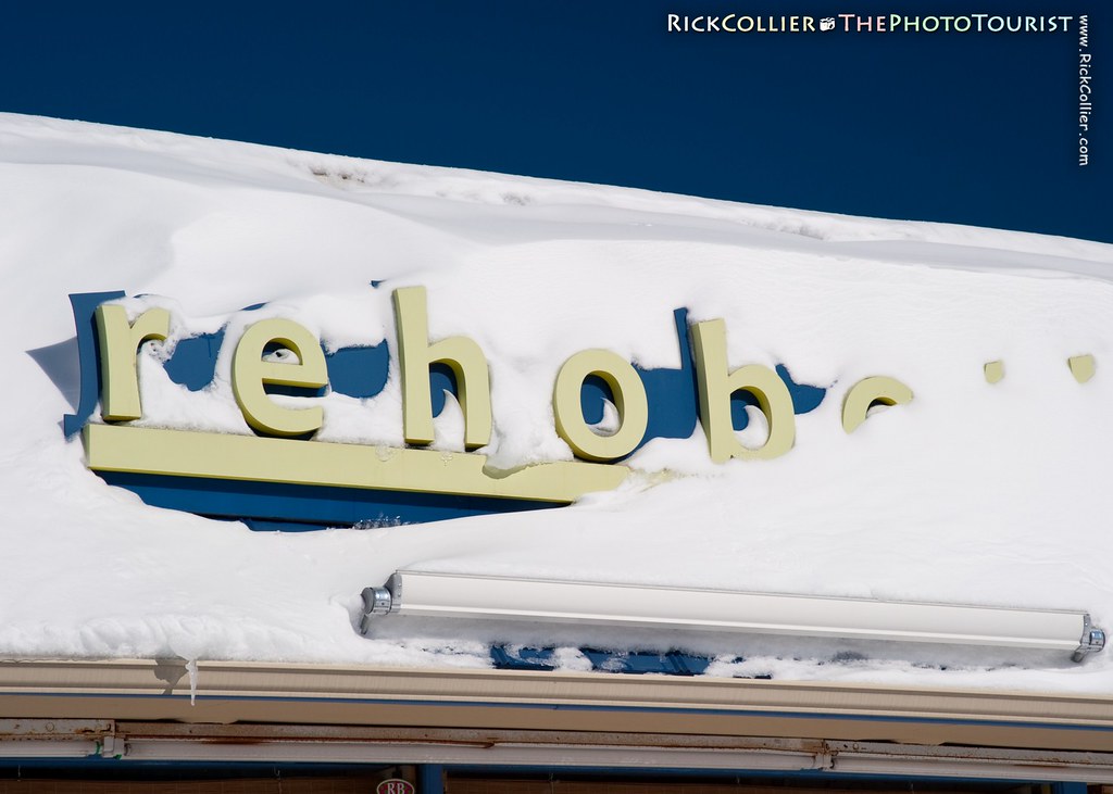 A store sign reading 'Rehoboth' is mostly buried under a layer of drifted snow.