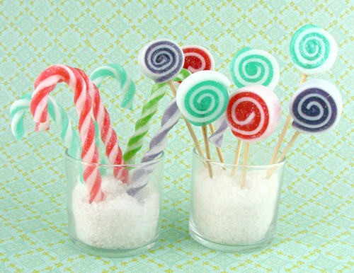 candy canes made of soap, standing in a cup, along with a cupful of spiral soap lollipops in various colours