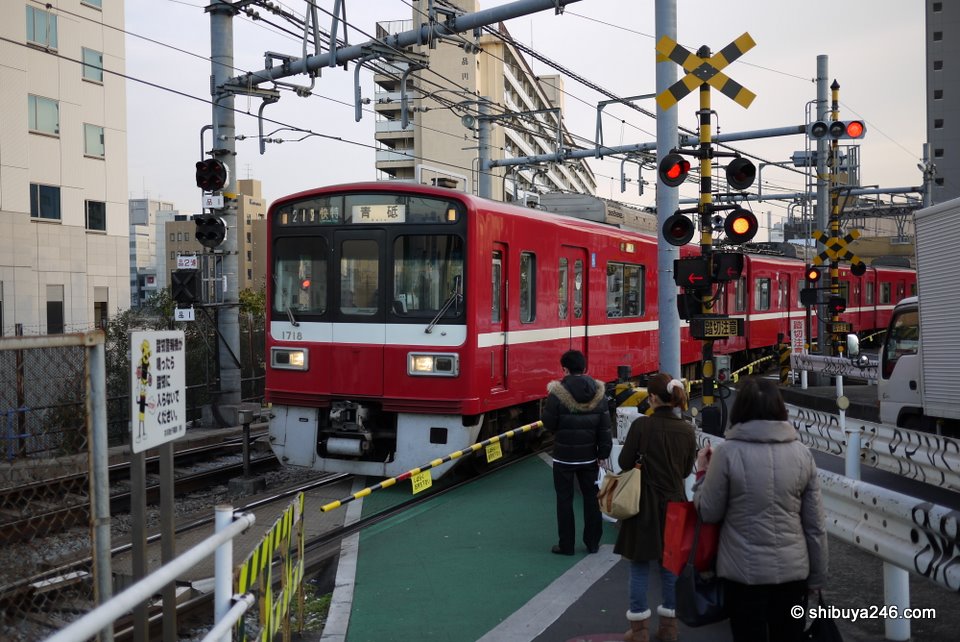 The Keihin Kyuko Line passes a level crossing as it heads towards Shinagawa Station.