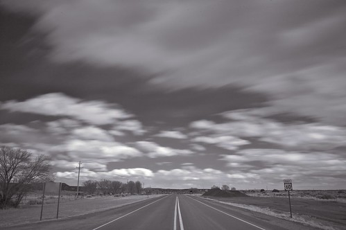 black 'n white photograph of a two-lane highway in new mexico, and enormous clouds and sky