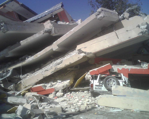 A leveled multi-story structure illustrates the earthquake's force. 