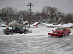 Snowplow trucks double teaming a parking lot after a heavy lake effect snowstorm. River Grove Illinois. Febuary 2008.