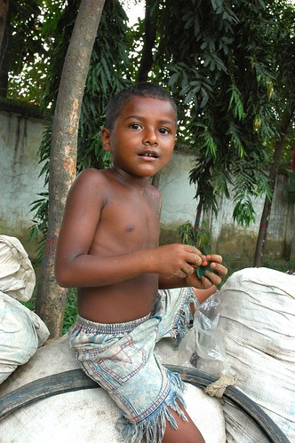 Portrait of a young boy, on white bags, Dhaka, Bangladesh by Wonderlane