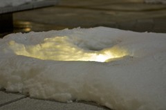 A light melts snow on a bench at Van Ness UDC
