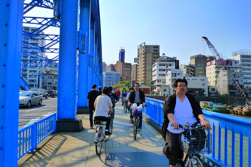 People cycling past one of the many Sumida River bridges