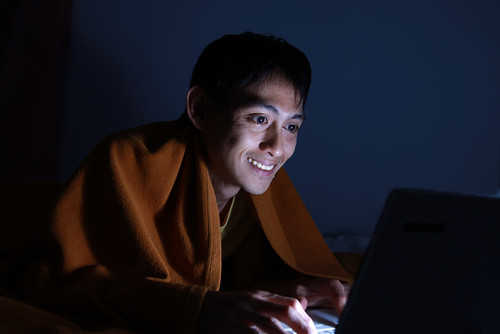 Man uses  computer in bed.