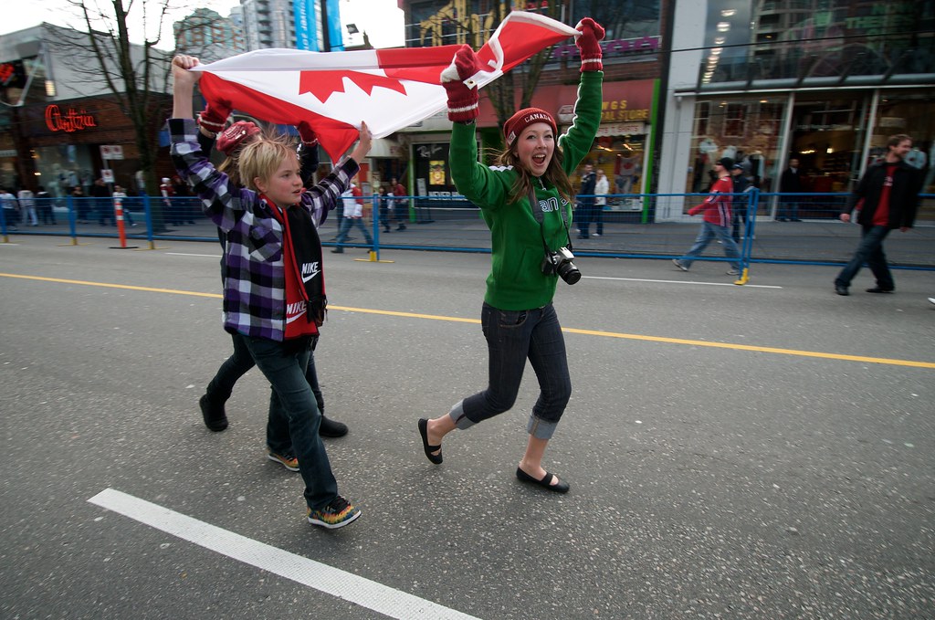 Kids Celebrate by Running in the Street with a Canadian Flag