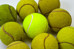 Brand new tennis ball among eight used ones