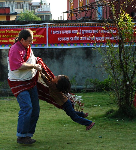 Joy! -Tashi, wearing his adi, spinning a little Tibetan girl in the air, Tharlam Monastery Courtyard, Boudha, Kathmandu, Nepal by Wonderlane