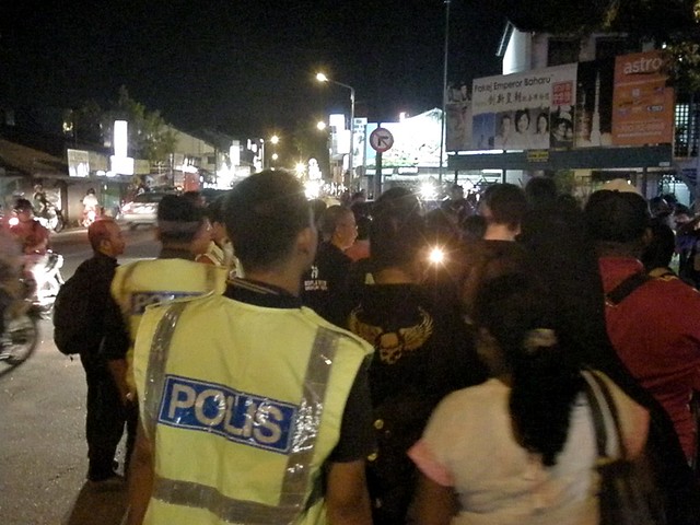 A lone candle burns brightly in the night as police close in on anti-ISA protesters outside the Jelutong Police Station