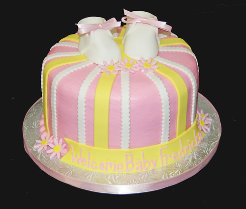pink and yellow striped baby shower cake wiht booties and daisies