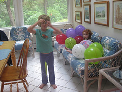 Speck sitting in a heap of balloons, while cousin S demonstrates a wiggly critter