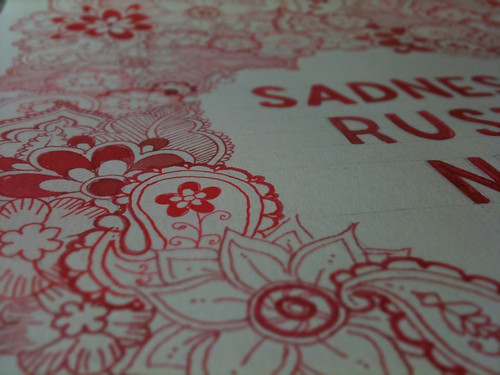 A close up photo of one of my drawings, paisley type shapes and flowers and some cut off text all drawn in red ink.