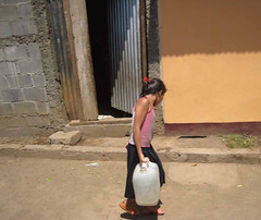 Young girl carrying water along a street in Ma...