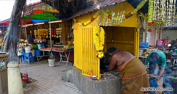 The priest cleaning up the shrine housing a figurine of Ganesh 