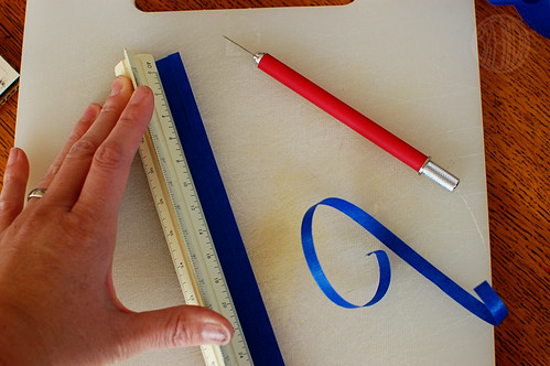 cutting strip of blue paper using a ruler and exacto knife