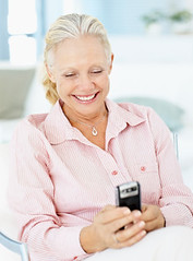 Senior woman smiles after reading a text message on cell phone by techsavvydaughter