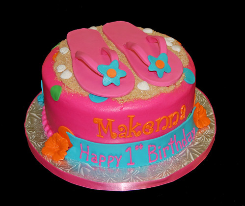 Bright colored luau themed first birthday cake with flip flops