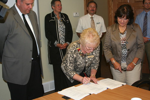 Joy McCracken – NeighborWorks Executive Director signs the Cooperative Packaging Agreement while State Director Elsie M. Meeks and Don Harris – Outreach Initiative Team Leader (USDA Rural Development National Office – Washington, DC) look on.
