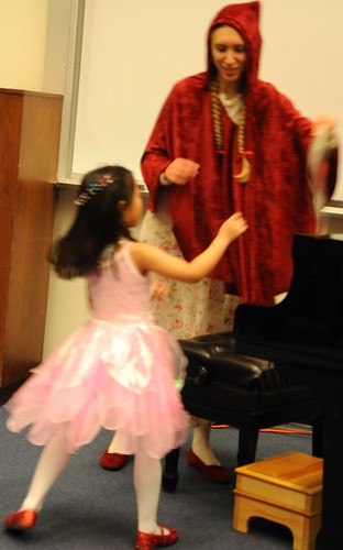 The Piano Recital, A pink fairy and Little Red Riding Hood both wearing red shoes, piano, step stool, University of Alaska Arts building, Anchorage, Alaska, USA by Wonderlane