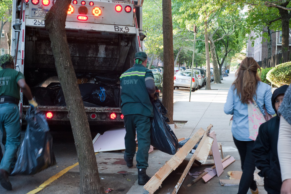 NYC sanitation workers throw garbage on side walk obstructing parents & children  near PS 102