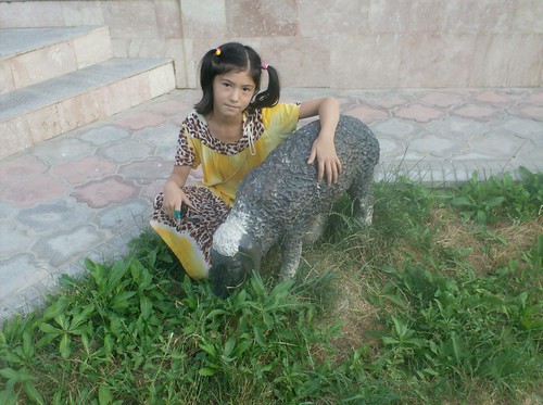 Young Tajik girl with sheep statue at Boq-i botaniki in Dushanbe, Tajikistan