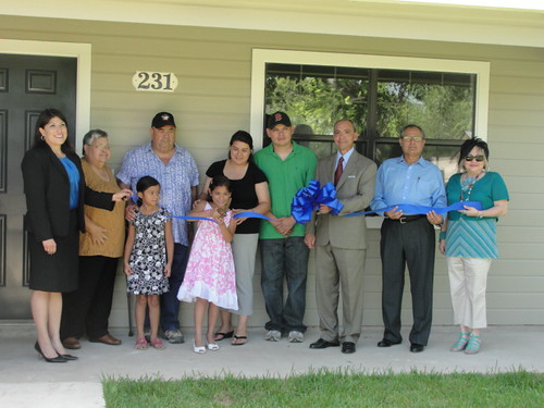 The Reanna Fernandez family proudly cuts a ribbon symbolic of starting their new life in a home they helped construct.  (State Director Paco Valentin is third from the right.)  