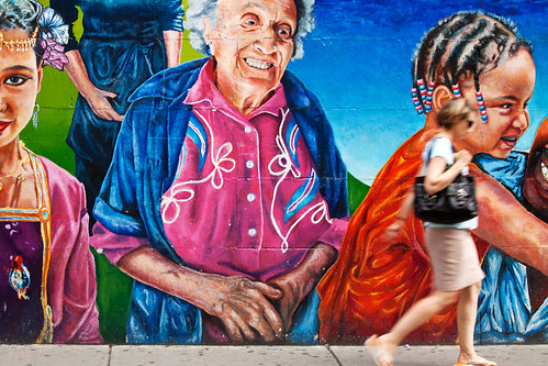 woman walking in front of mural