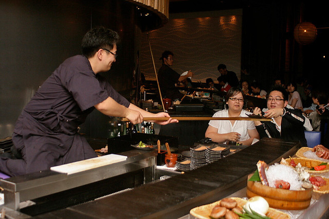 The chef delivers the food using the wooden oar or paddle