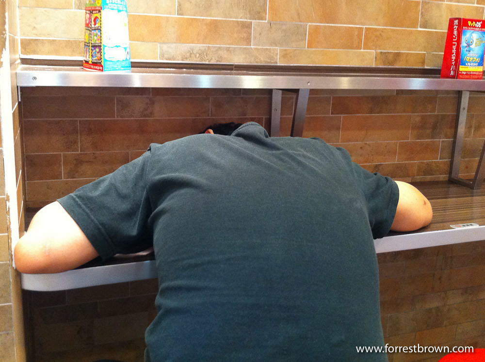 Person sleeping in a Japanese fast food restaurants.
