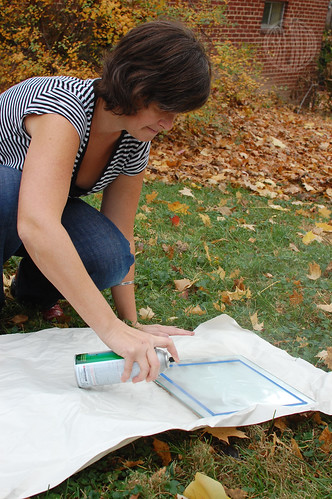 woman spraying paint onto a frame 