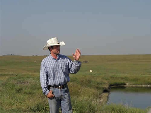 Dan Imthurn stands by lagoon, a part of his agricultural waste system, with rangeland behind him. Dan captures the wastes from his feedlot and applies the manure to his land as a fertilizer. His efforts protect the water quality in nearby Mill Creek while improving the productivity of his land.