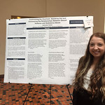 A student standing next to her research poster