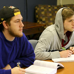 Two students listening intently as they take notes in class.