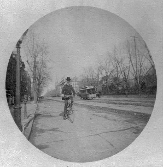 : [Man on bicycle on street, Washington, D.C., with horse-drawn streecar in background]