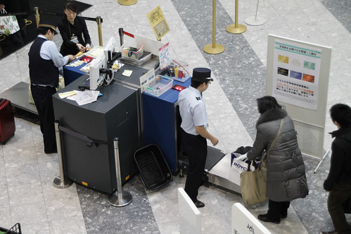 Airport security staff x-ray luggage in Japan.