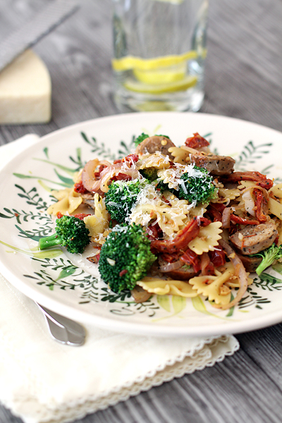 A plate of bow tie pasta with sausage and broccoli. 