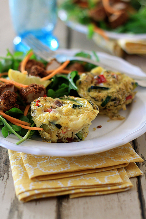 Two breakfast frittata muffins on a plate with a side salad 