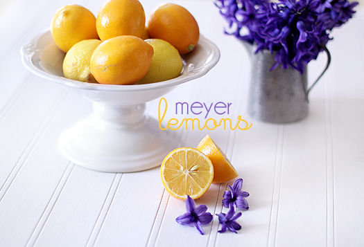 A bowl of lemons with lilacs in the background. 