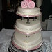 3 tier wedding cake with heart shaped cakes and detailed pink flowers on top.