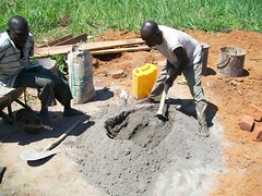 A local man helps mix concrete