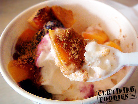 A spoonful of Yogiberry peach-flavored frozen yogurt with peach and crushed graham - CertifiedFoodies.com